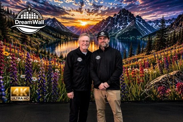 Gary Wermuth and Noah Meicler standing in front of a DreamWall MicroLED video wall displaying a mountain sunset