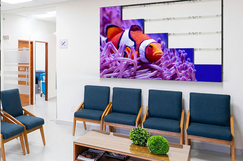 A partially installed LED video wall displaying a clownfish image in a medical waiting room, with rear mounting structure exposed on the right