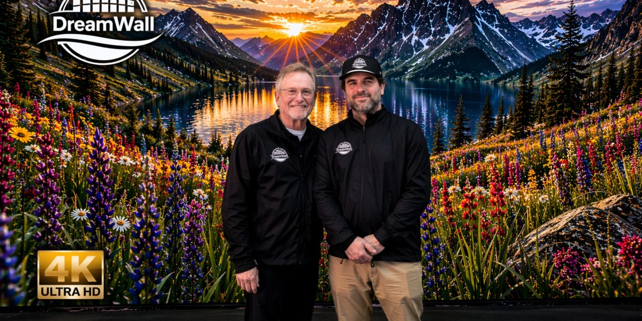 Gary Wermuth and Noah Meicler standing in front of a 4K DreamWall MicroLED CooLED video wall displaying a mountain lake at sunset with wildflowers